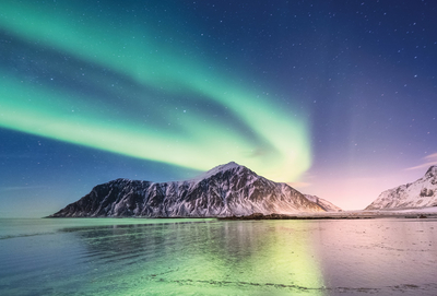 Northern light above mountains and sea shore