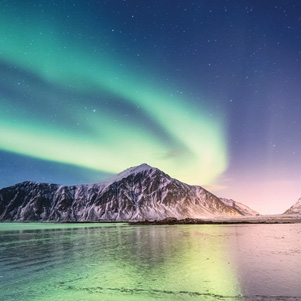 Northern light above mountains and sea shore